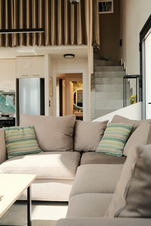 A modern living room with a sectional sofa, a small table, and a staircase leading to an upper level.