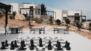 Un tablero de ajedrez al aire libre, con edificios modernos al fondo.
