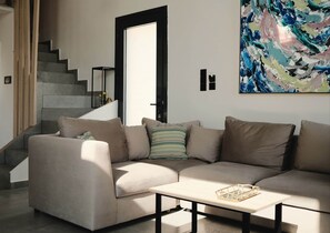 Un salon moderne avec un canapé d’angle beige, une table basse et un escalier.