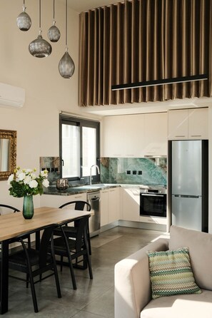 A modern kitchen with a dining area, a sofa, and a decorative vase. - T H A L I A  -  Aelia Horizon Villas (Corinth)