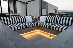 A modern outdoor seating area with a sectional sofa and a built-in heated floor.