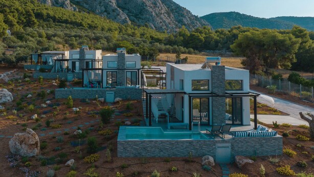A modern resort with multiple villas, each featuring a private pool and a view of the surrounding mountainous landscape.