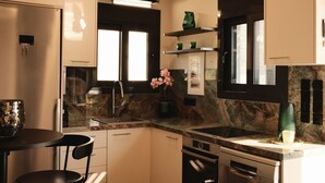 A compact kitchen with a sink, stove, and dishwasher. There is a small dining area with a table and chairs.
