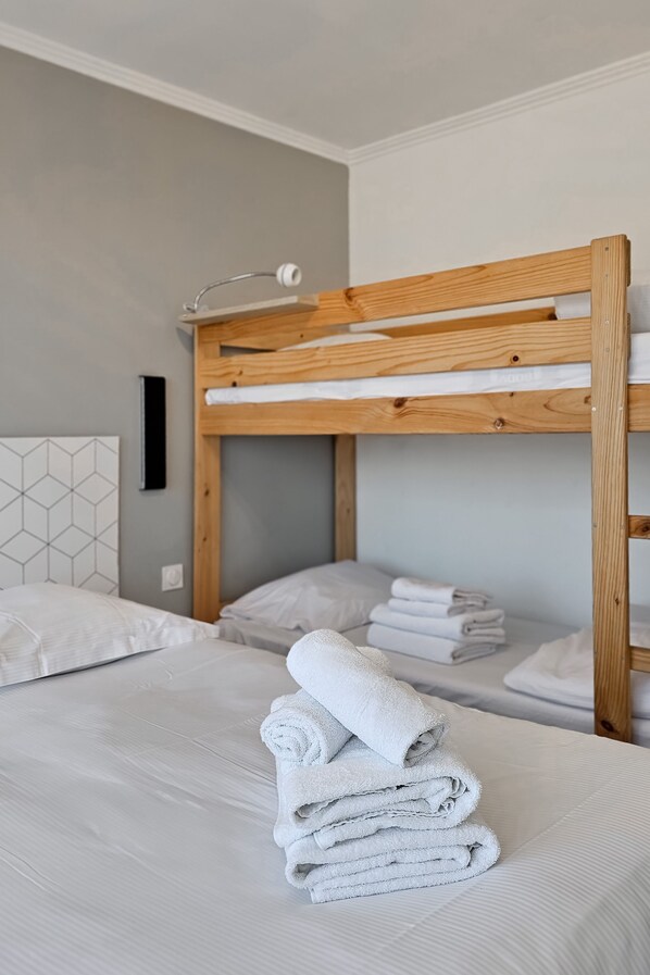 A bunk bed with a wooden frame, white bedding, and a folded towel on the lower bunk.