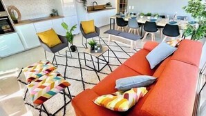A modern living room with a red sofa, a coffee table, and a dining area with a table and chairs.