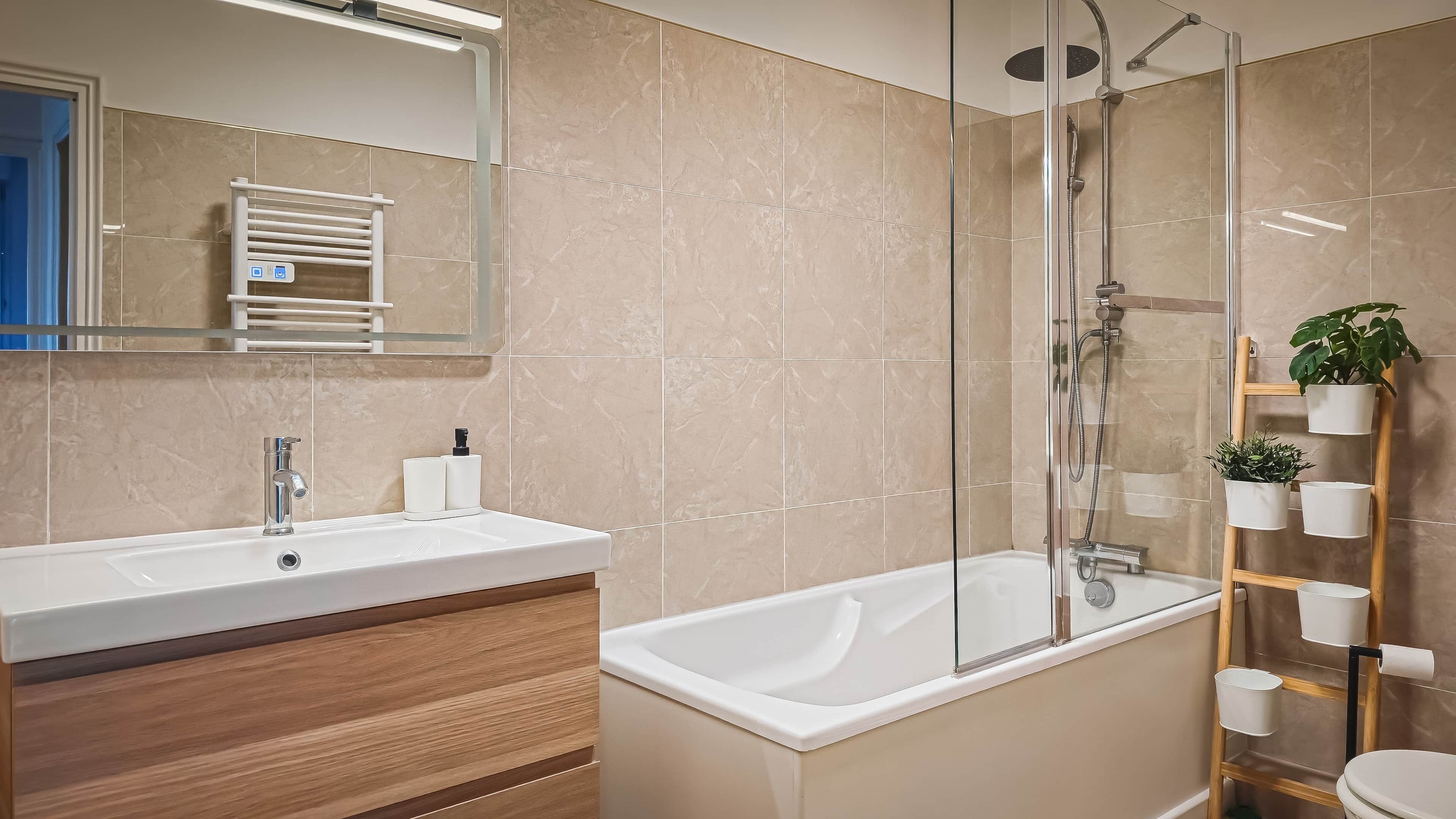 A modern bathroom with a sink, mirror, and shower.