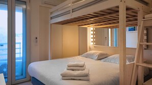 Habitación de hotel con cama, ventana, balcón y estructura de techo de madera.