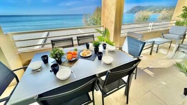 Un balcón con una mesa lista para comer, con vistas a la costa.
