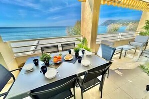 Un balcón con una mesa lista para comer, con vistas a la costa.