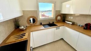Una cocina moderna con ventana, armarios blancos y encimera de madera.