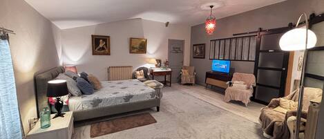 A cozy bedroom with a bed, bedside tables, a dresser, a TV, and a chair.