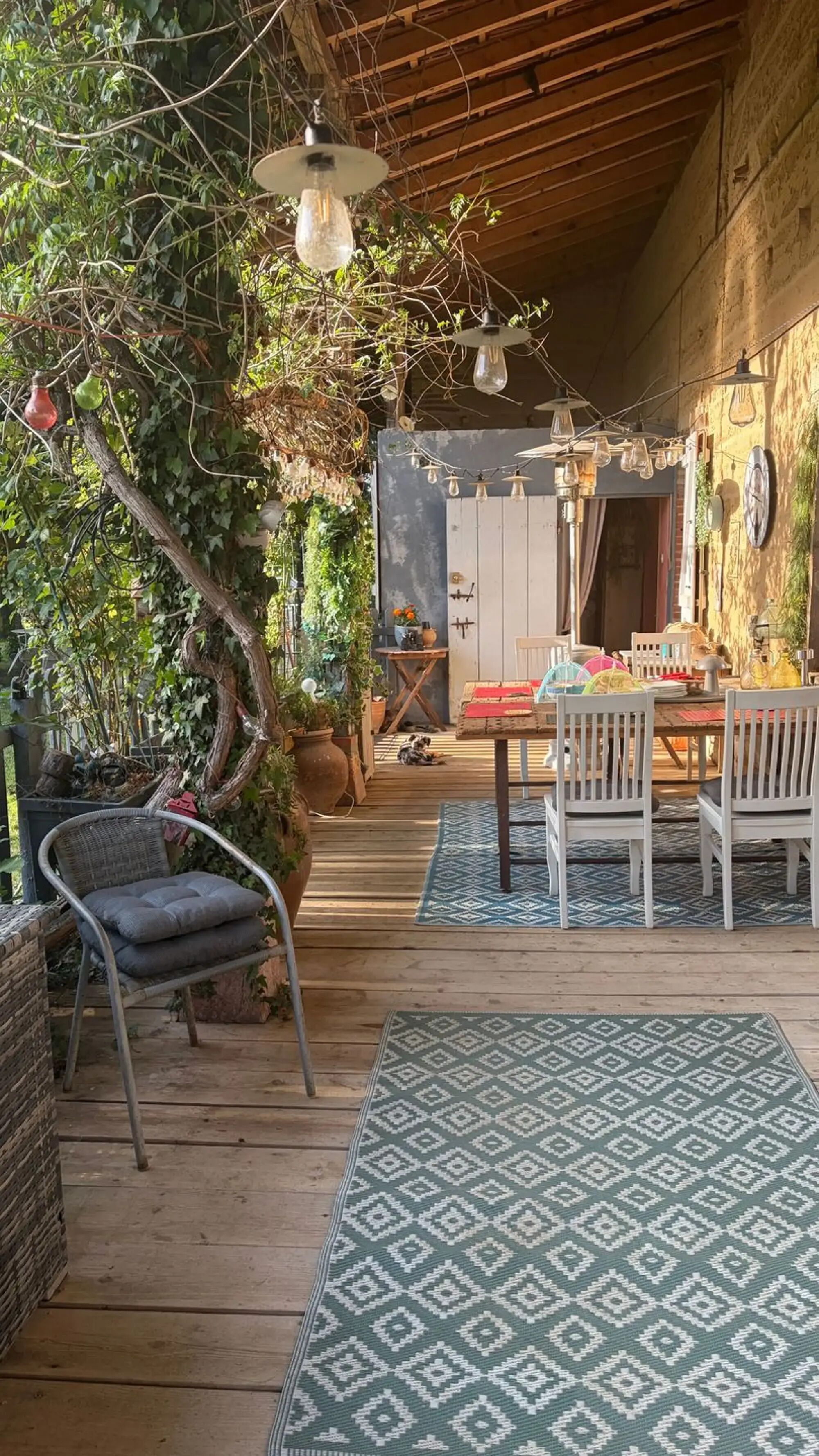 Un'accogliente terrazza in legno con zona pranzo, sedie e tavolo.