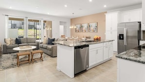 Una cocina moderna con una isla central, armarios blancos y un refrigerador de acero inoxidable.