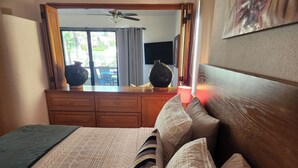 Une chambre à coucher comprenant un lit, une commode, un ventilateur de plafond et une vue sur l’extérieur.