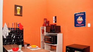 Uma cozinha compacta com uma mesa de madeira, micro-ondas, máquina de café e geladeira.