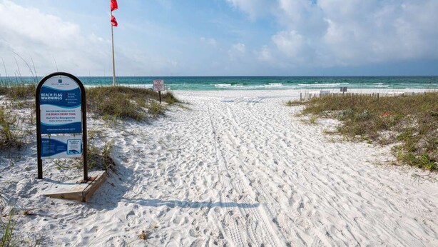 A sandy beach path leading to the ocean with a beach flag warning sign and a red flag indicating high surf. - HUGE % OFF, Private Pool ☀️ Walk to Beach, Screened Porch, 6 Bdrm ☀️ Big Driveway (Seagrove Beach)
