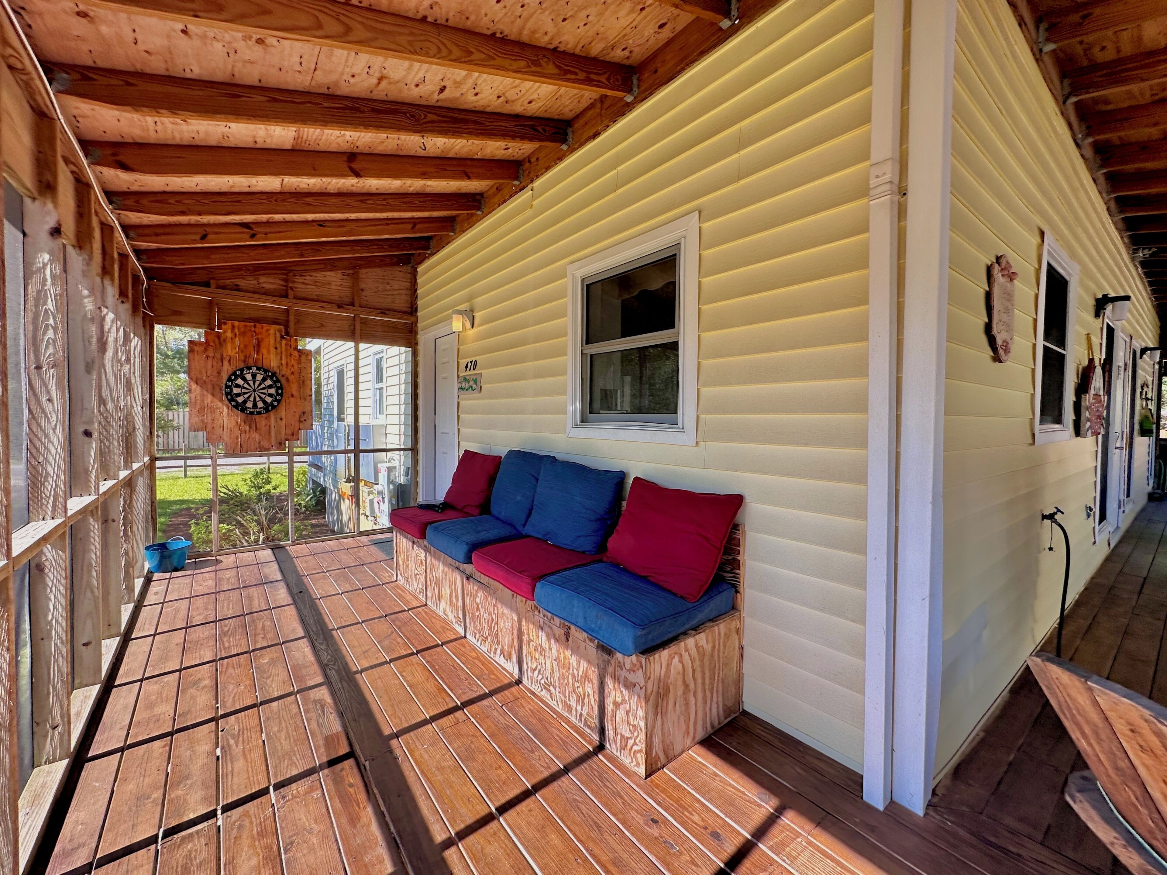 A covered porch with a wooden bench and a dartboard.