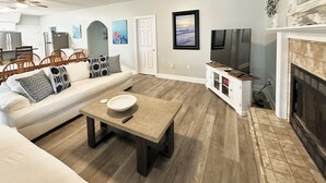 A living room with a beige sofa, a coffee table, and a fireplace. - HUGE % OFF, Private Pool ☀️ Walk to Beach, Screened Porch, 6 Bdrm ☀️ Big Driveway (Seagrove Beach)