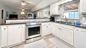 A modern kitchen with white cabinetry, a stainless steel stove, and a large window. - HUGE % OFF, Private Pool ☀️ Walk to Beach, Screened Porch, 6 Bdrm ☀️ Big Driveway (Seagrove Beach)