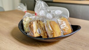 A bowl containing several wrapped pastries on a wooden table in a kitchen setting. - SAN GIOVANNI COZY APT - HOME AND MORE (Roma)