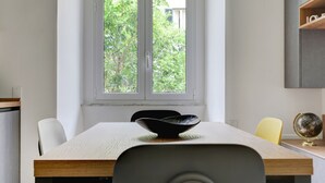 A modern dining area with a large window, a wooden table, and a bowl on the table. - SAN GIOVANNI COZY APT - HOME AND MORE (Roma)