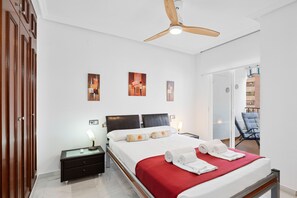 Ett hotellrum med en säng, sängbord, en takfläkt, konstverk på väggen och utsikt över omgivningarna.