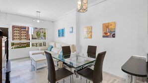 A modern living room with a glass dining table, leather chairs, a white sofa, and artwork on the walls. - Ref. 493702 (Almuñecar)