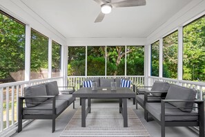 A covered patio area with a table and chairs, large windows, and a ceiling fan. - Your Cape State of Mind Adventure Awaits! (South Yarmouth)