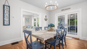 A dining area with a wooden table, blue chairs, and a chandelier. - Your Cape State of Mind Adventure Awaits! (South Yarmouth)
