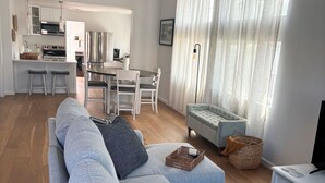 Un salon moderne avec un canapé gris, un coin repas et une cuisine en arrière-plan.