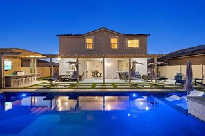 Una casa de dos pisos con una piscina en primer plano.