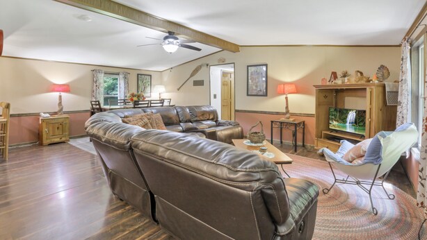 A living room with a sectional sofa, a television, and a ceiling fan. - Redhead Hollow Cottage | Hocking Hills, Hot Tub (Rockbridge)