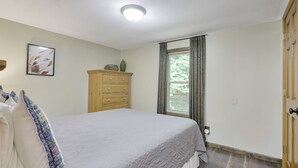 A bedroom with a bed, a dresser, a window with curtains, and a ceiling light. - Redhead Hollow Cottage | Hocking Hills, Hot Tub (Rockbridge)