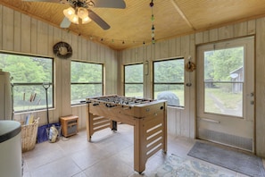 A wooden-floored room with a foosball table, large windows, and a ceiling fan. - Redhead Hollow Cottage | Hocking Hills, Hot Tub (Rockbridge)