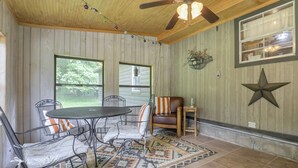 A covered patio area with a table and chairs, a ceiling fan, and a star decoration on the wall. - Redhead Hollow Cottage | Hocking Hills, Hot Tub (Rockbridge)