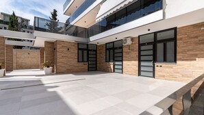 Moderni rakennus, jossa on tilava patio, suuret ikkunat ja pelkistetty muotoilu.