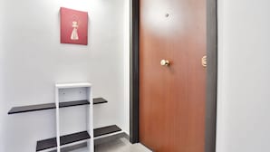 Un couloir avec une porte en bois, une étagère blanche et un tableau encadré accroché au mur.