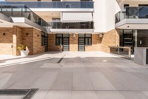 A modern building with a courtyard, glass balconies, and a mix of brick and concrete walls.