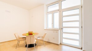A room with a dining table, two chairs, a window with blinds, and a door. - GuestHost - Cozy 62 sqm apartment in Trani, ideal for 4 people. Located on the ground floor, it includes a reserved outdoor parking space. Just a short walk from the center of Trani, it offers easy access to all the main attractions. Trani is a charming  (Trani)