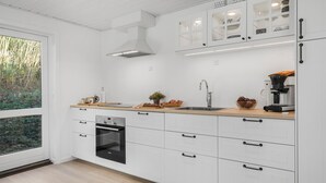 A modern kitchen with white cabinetry, a built-in oven, and a large window overlooking greenery. - Awesome home in Korsør with WiFi (Korsør)