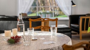 A round table with a lace tablecloth, candles, a bottle, glasses, and playing cards. - Awesome home in Korsør with WiFi (Korsør)