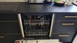 Uma cozinha com lava-louças embutida, torradeira e chaleira na bancada.