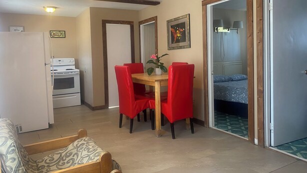 Un espace de vie compact comprenant un coin repas, une kitchenette et une chambre.