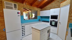 Una cocina con armarios blancos, una isla central, una estufa y un microondas.