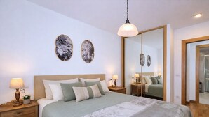 A bedroom with a large bed, bedside tables with lamps, a hanging light fixture, and two wall-mounted mirrors. - Llanes Celorio Swimming Pool and Beach - El Castro Borizu (Celorio (Llanes))