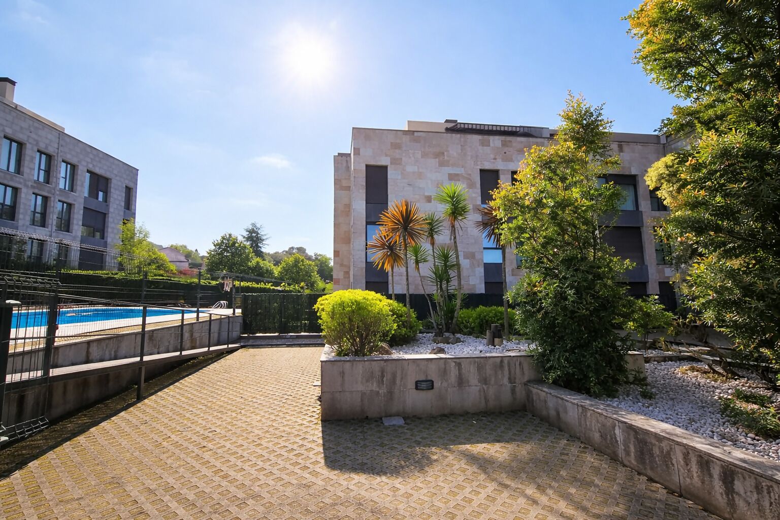 A courtyard with a swimming pool, surrounded by buildings and greenery.