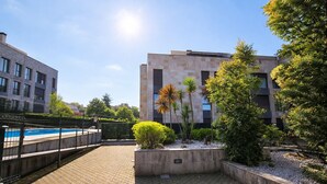 A courtyard with a swimming pool, surrounded by buildings and greenery. - Llanes Celorio Swimming Pool and Beach - El Castro Borizu (Celorio (Llanes))