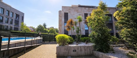 A courtyard with a swimming pool, surrounded by buildings and greenery.