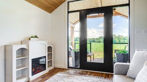 Una sala de estar moderna con chimenea, un sofá y vistas de un jardín a través de un amplio ventanal corredero.