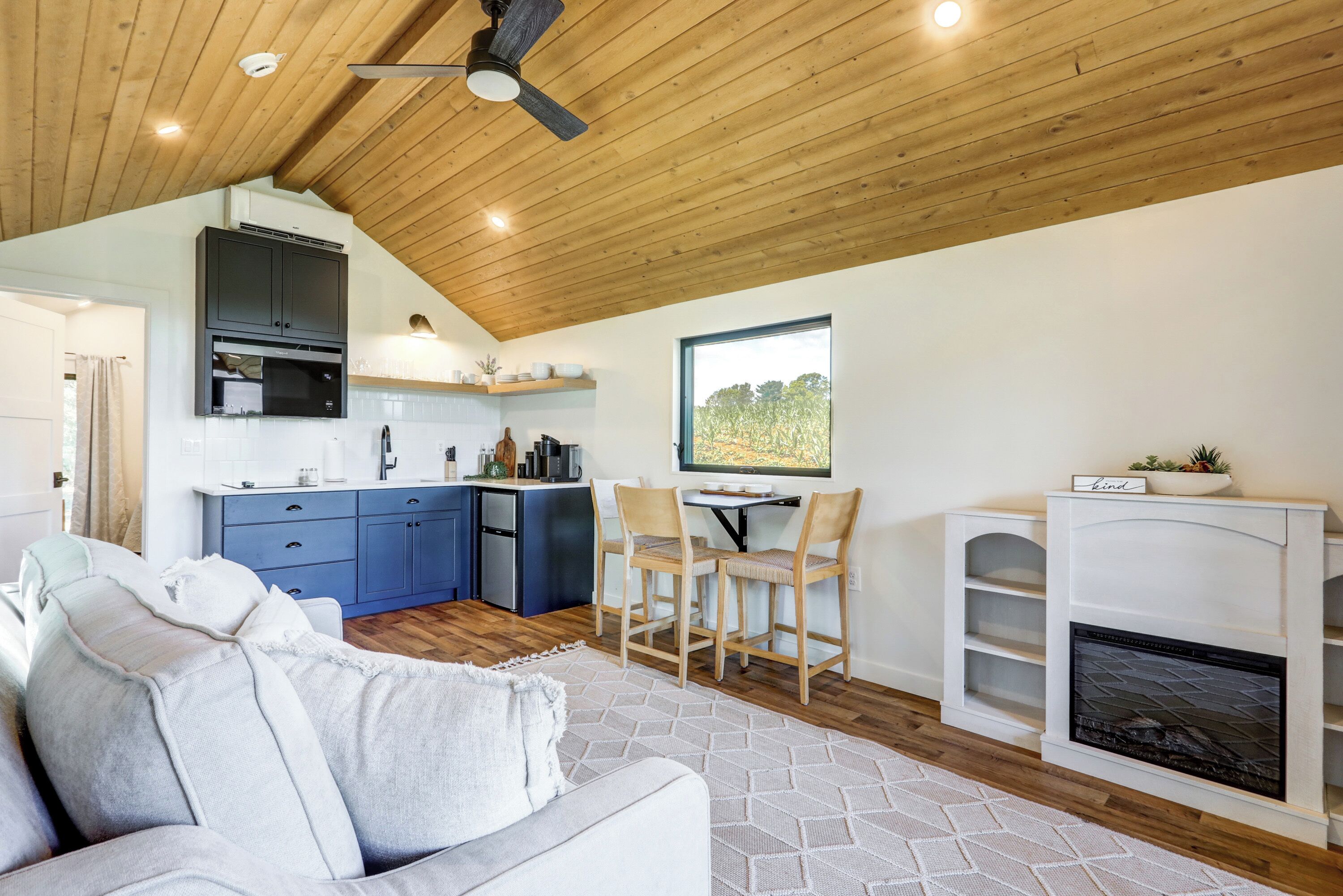 A modern kitchen with blue cabinets, a dining area with wooden chairs, and a fireplace.